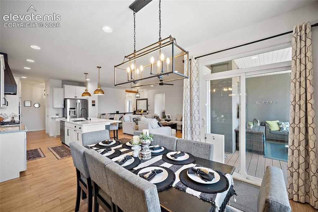 Image 11 of 46: Open-concept dining area featuring a linear chandelier with exposed bulbs, 