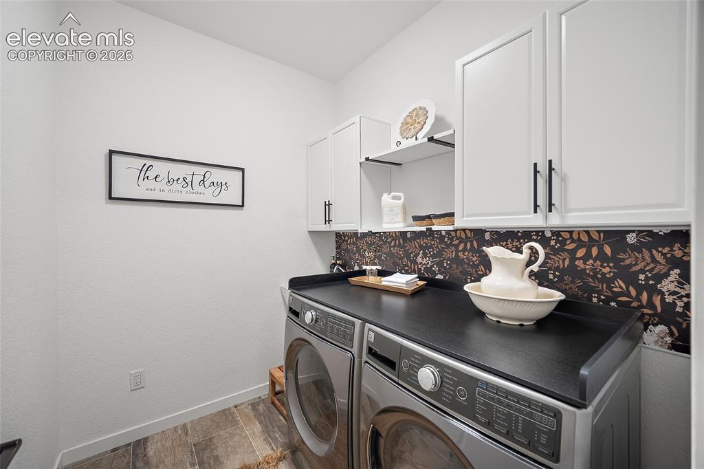 Image 15 of 46: Laundry room featuring white shaker-style cabinetry, a dark solid-surface c