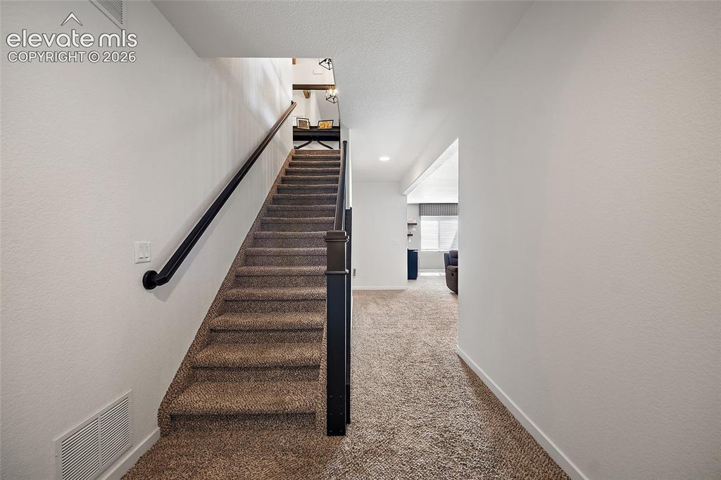Image 25 of 46: Carpeted staircase with black handrail and newel post