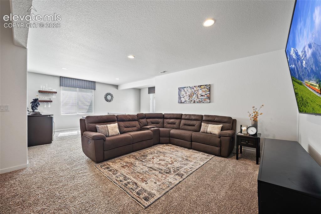 Image 26 of 46: Spacious carpeted room featuring recessed lighting and a built-in wet bar w