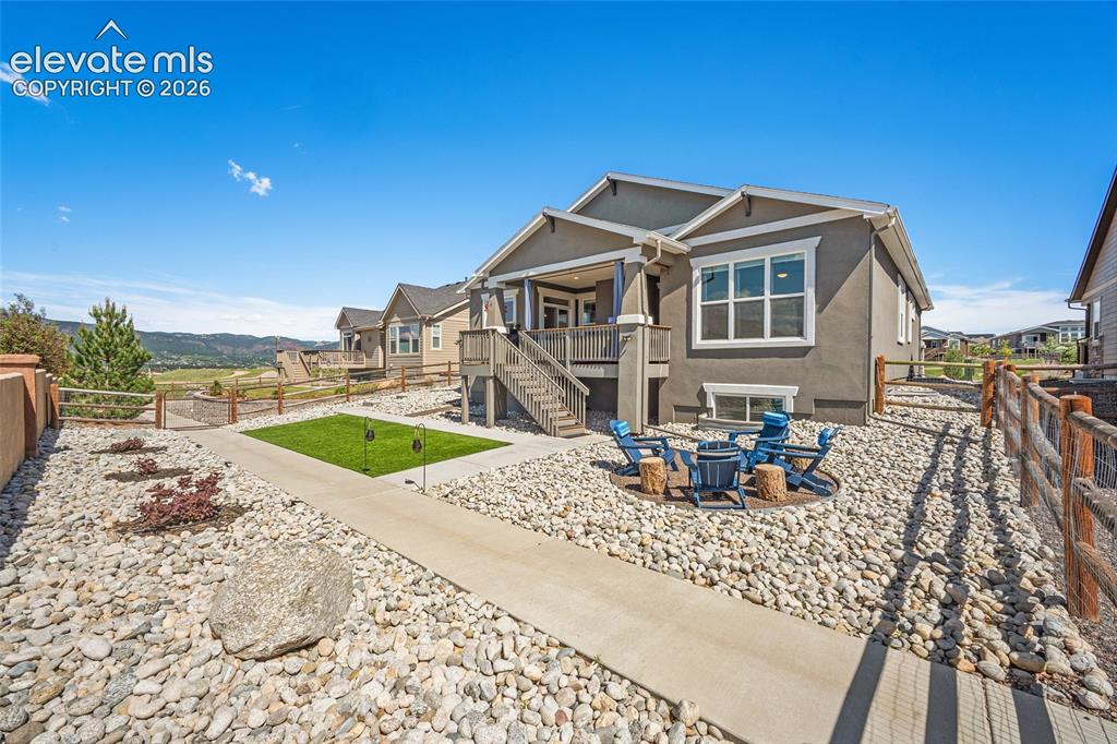 Image 35 of 46: Rear exterior featuring a stone fire pit area, covered balcony, and sloped 
