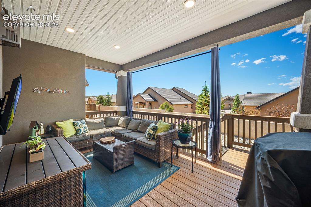 Image 38 of 46: Covered outdoor deck featuring composite flooring, wood railing, and recess