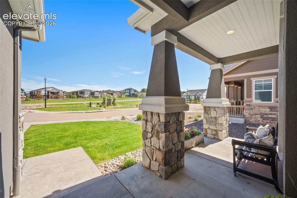 Image 41 of 46: Covered porch with stone-clad columns and a beadboard ceiling