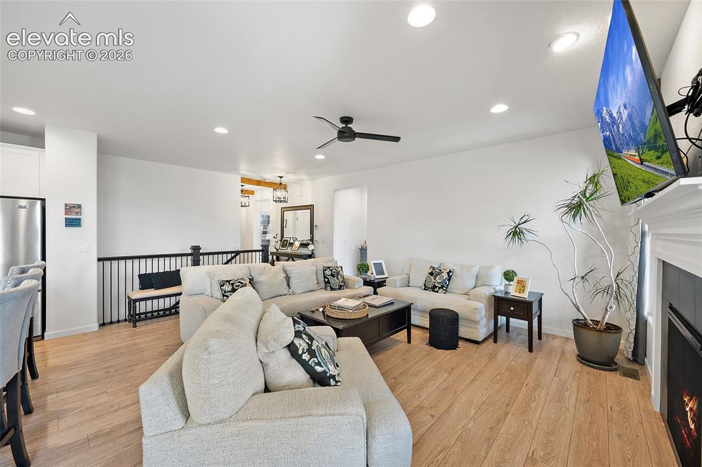 Image 7 of 46: Living area featuring wood-finish flooring, recessed lighting, and a black 