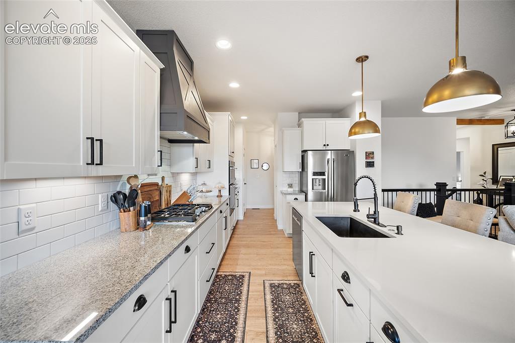 Image 9 of 46: Spacious kitchen featuring white shaker cabinetry, granite countertops, a s