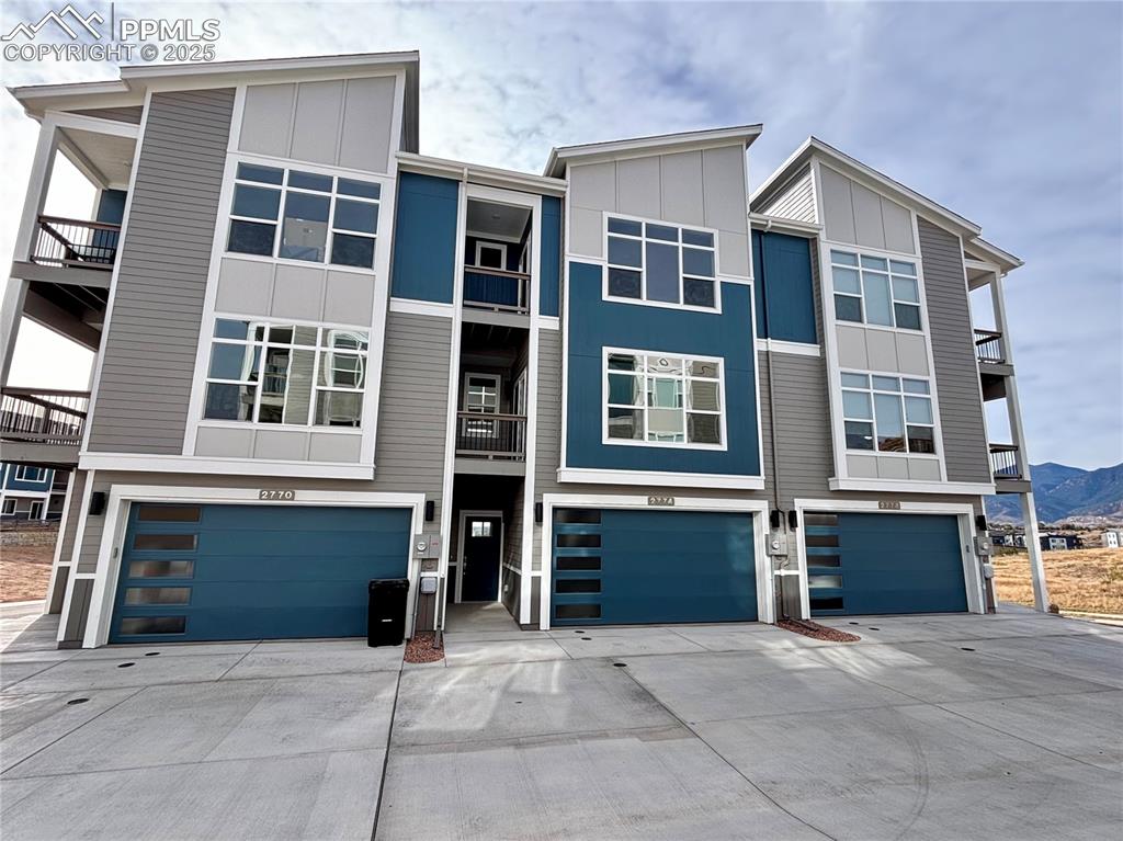 Image 2 of 14: Modern home featuring board and batten siding, driveway, an attached garage