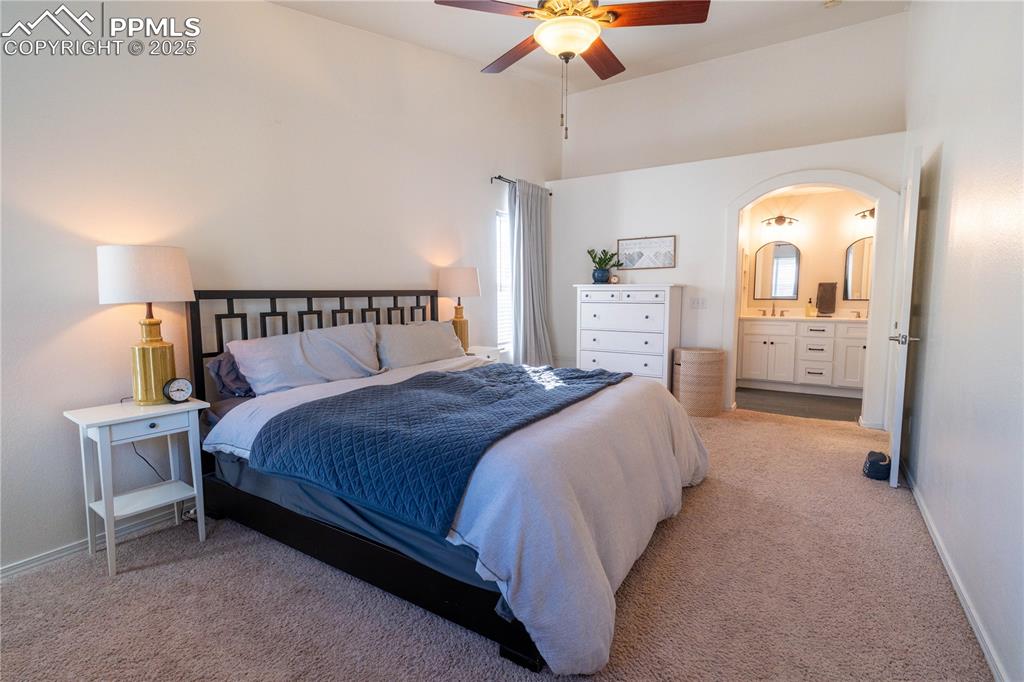 Image 11 of 26: Bedroom featuring light colored carpet, ceiling fan, arched walkways, and e