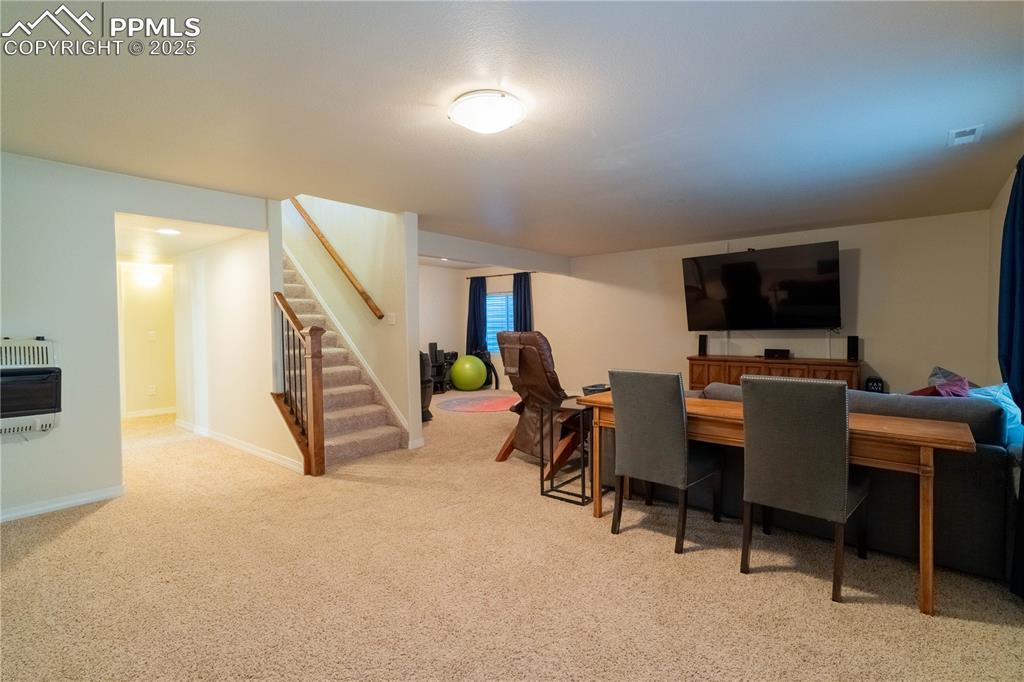 Image 20 of 26: Carpeted dining space featuring heating unit and stairway