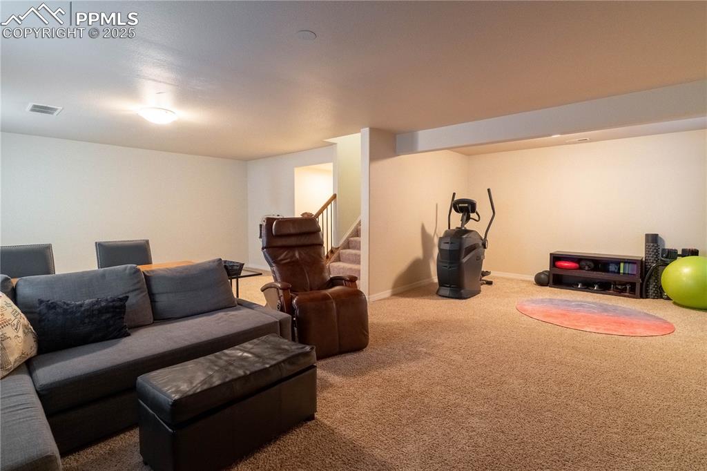 Image 21 of 26: Living room with carpet floors and stairway
