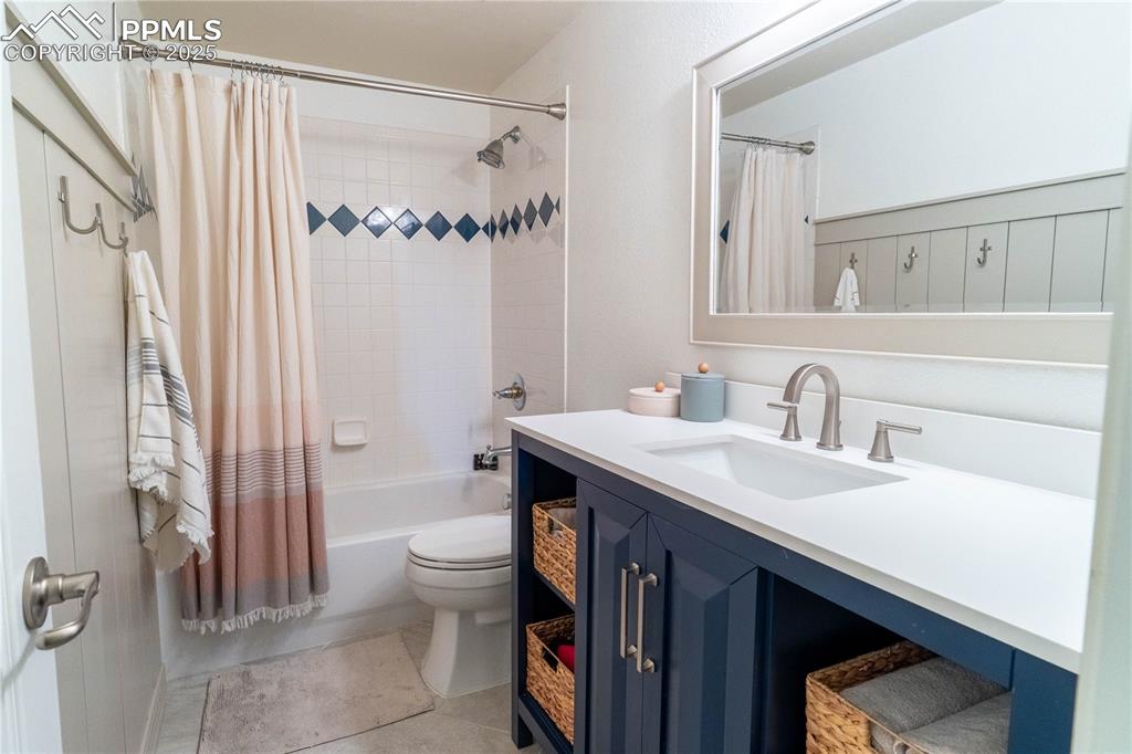 Image 22 of 26: Bathroom with shower / bathtub combination with curtain, vanity, and light
