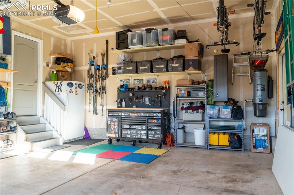 Image 26 of 26: Garage with freestanding refrigerator, a workshop area, and a garage door o