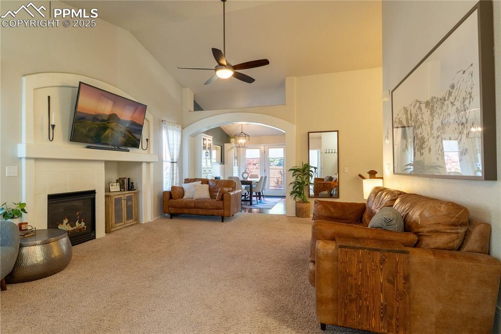 Image 6 of 26: Carpeted living area with a fireplace, arched walkways, lofted ceiling, a c