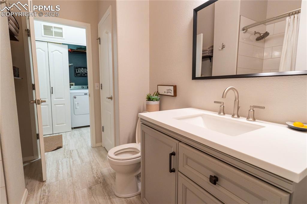 Image 7 of 26: Bathroom with vanity, washer / dryer, light wood-style floors, and a shower