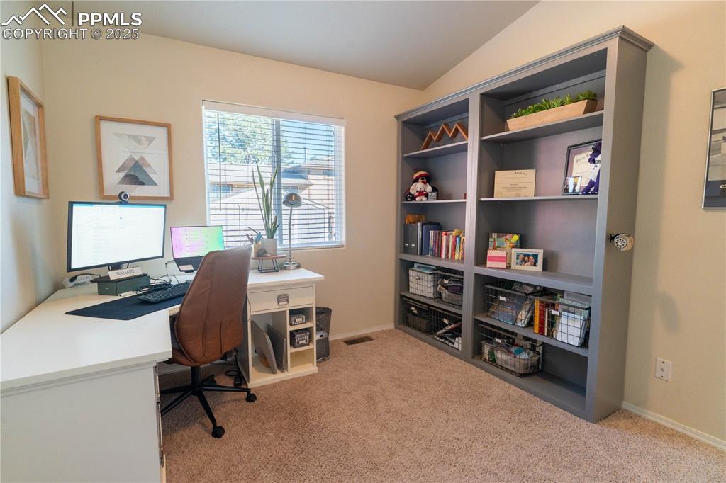 Image 9 of 26: Office space with light colored carpet and vaulted ceiling