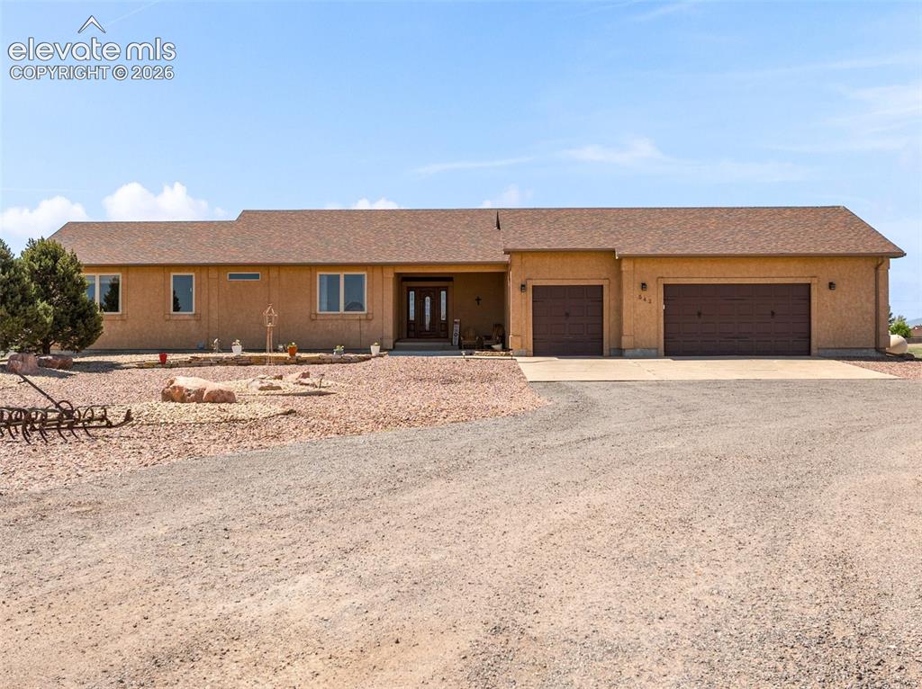 Caption: Single-story residence featuring a stucco exterior, brown shingle roof, and a multi-car garage with 