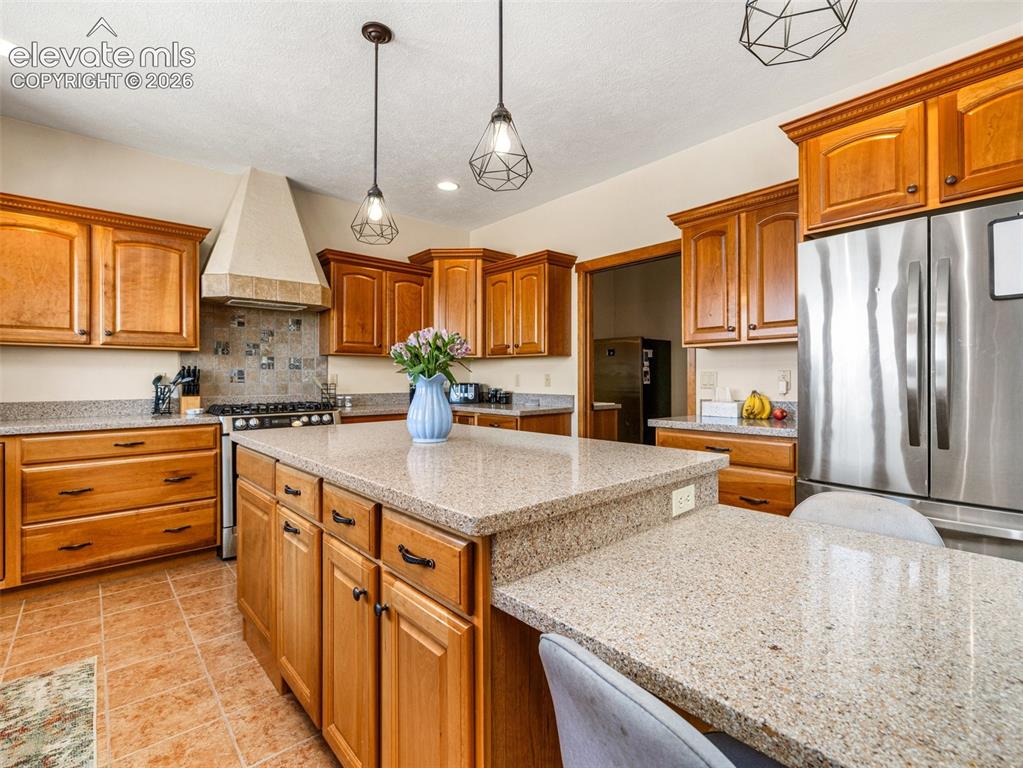 Image 10 of 44: Kitchen featuring wood cabinetry, stainless steel appliances, a multi-level