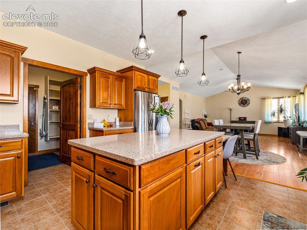 Image 11 of 44: Kitchen featuring wood cabinetry, a center island with a light-toned counte