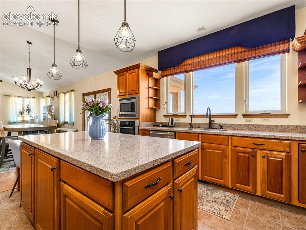 Image 12 of 44: Kitchen featuring wood cabinetry, a center island with a stone-finish count