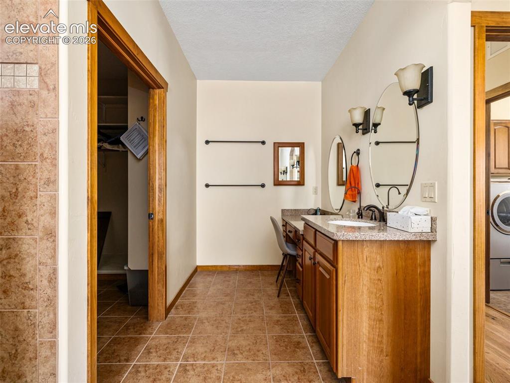 Image 15 of 44: Dual vanity with integrated sinks, speckled countertops, and wood-finish ca