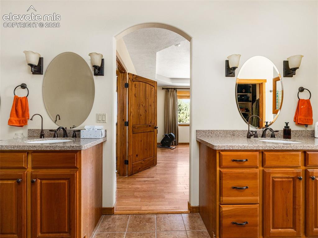 Image 18 of 44: Dual vanities with undermount sinks, speckled countertops, and individual o