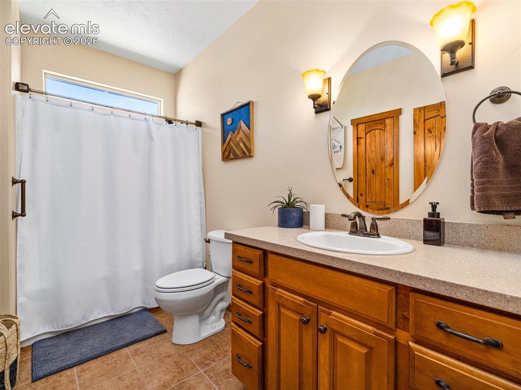 Image 22 of 44: Warm-toned wood cabinetry with dark hardware, a stone-finish countertop, an