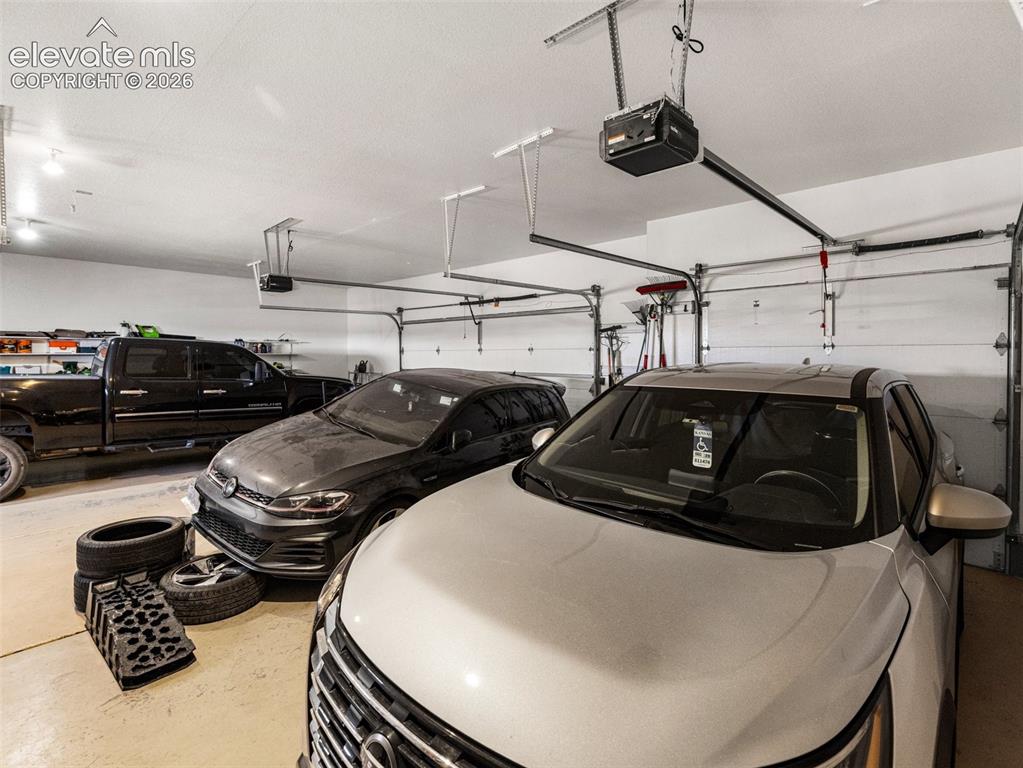 Image 32 of 44: Garage with concrete flooring, multiple overhead garage door openers, and t