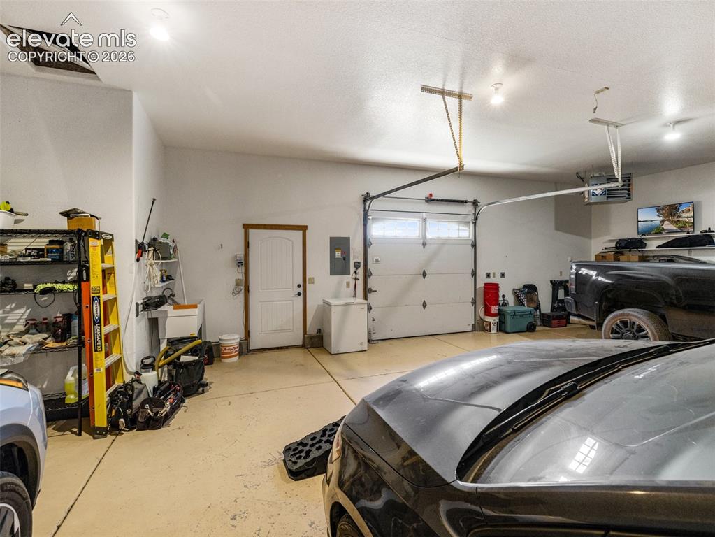 Image 33 of 44: Two-car garage featuring a roll-up garage door, painted concrete flooring, 