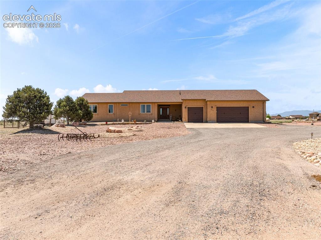 Image 36 of 44: Single-story stucco exterior with a multi-car garage, brown garage doors, a