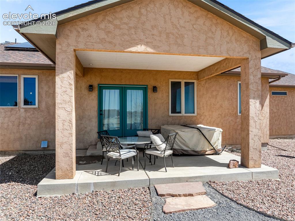 Image 42 of 44: Covered outdoor patio with textured stucco exterior, double-pane windows, a