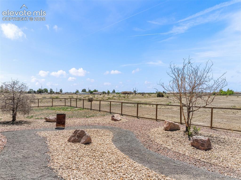 Image 43 of 44: Expansive outdoor space featuring a wood-panel fence, gravel pathways, and 