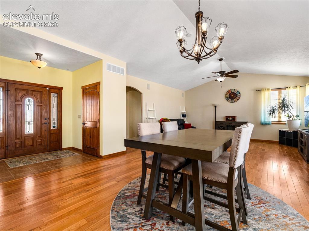 Image 5 of 44: Hardwood flooring, vaulted ceiling, arched doorway, ceiling fan, and decora