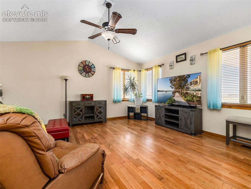 Image 6 of 44: Vaulted ceiling with a ceiling fan, wood-finish flooring, multiple windows