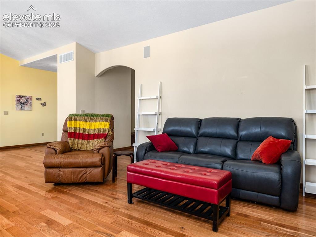Image 7 of 44: Warm-toned wood-finish flooring, an arched doorway, and light-toned walls