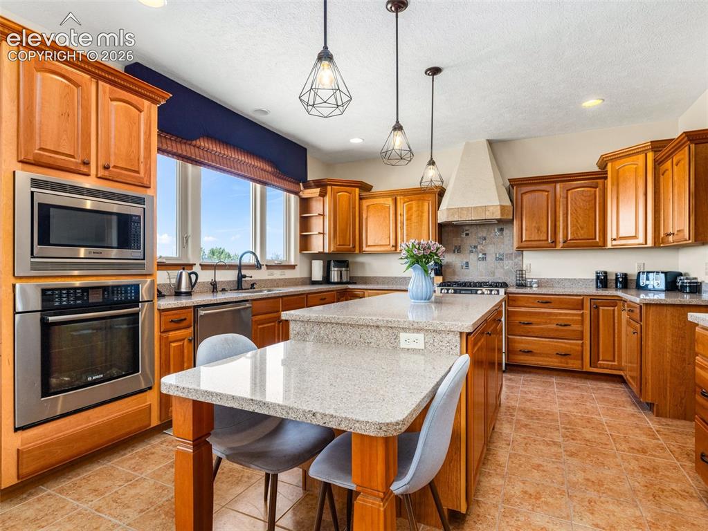 Image 9 of 44: Kitchen with wood-finish cabinetry, stainless steel appliances, a center is