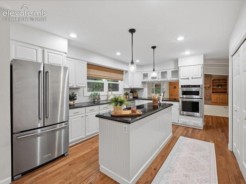 Image 13 of 49: View of kitchen, oven and microwave on wall, cooktop on island stainless st