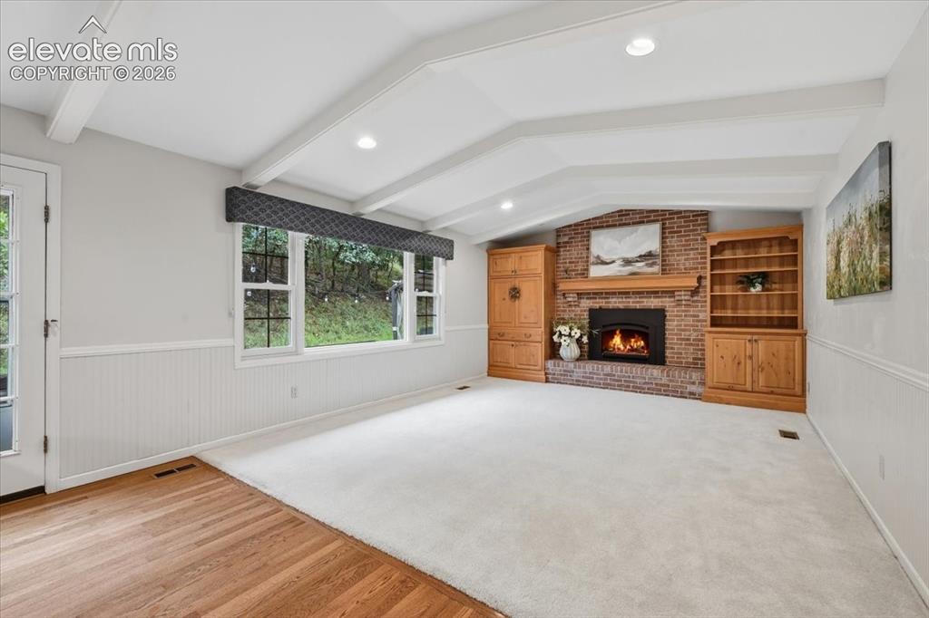 Image 16 of 49: Family room with door to back patio, gas fireplace and built ins. Vaulted
