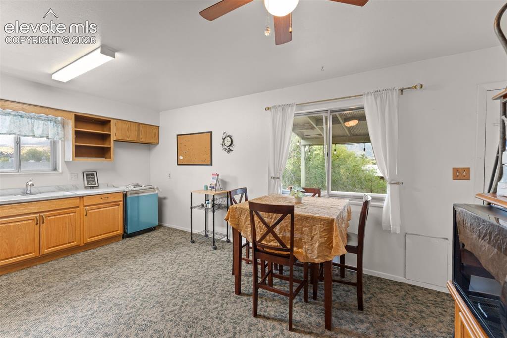 Image 13 of 50: Wood-finish cabinetry, built-in shelving, white countertops, ceiling fan wi