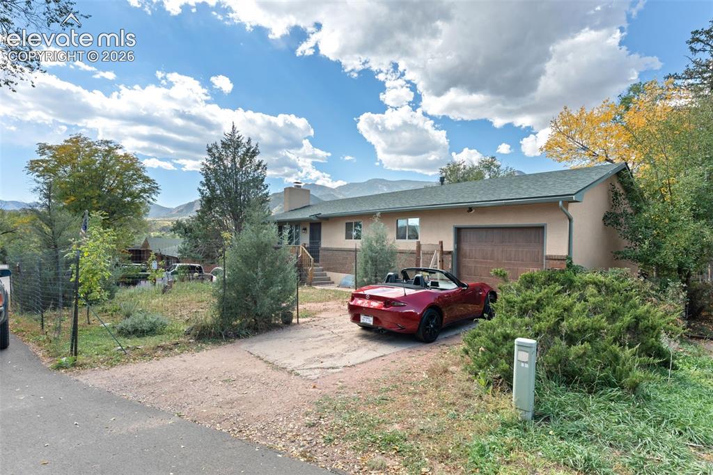 Image 22 of 50: Single-level residence with an attached garage, paved driveway, mature land