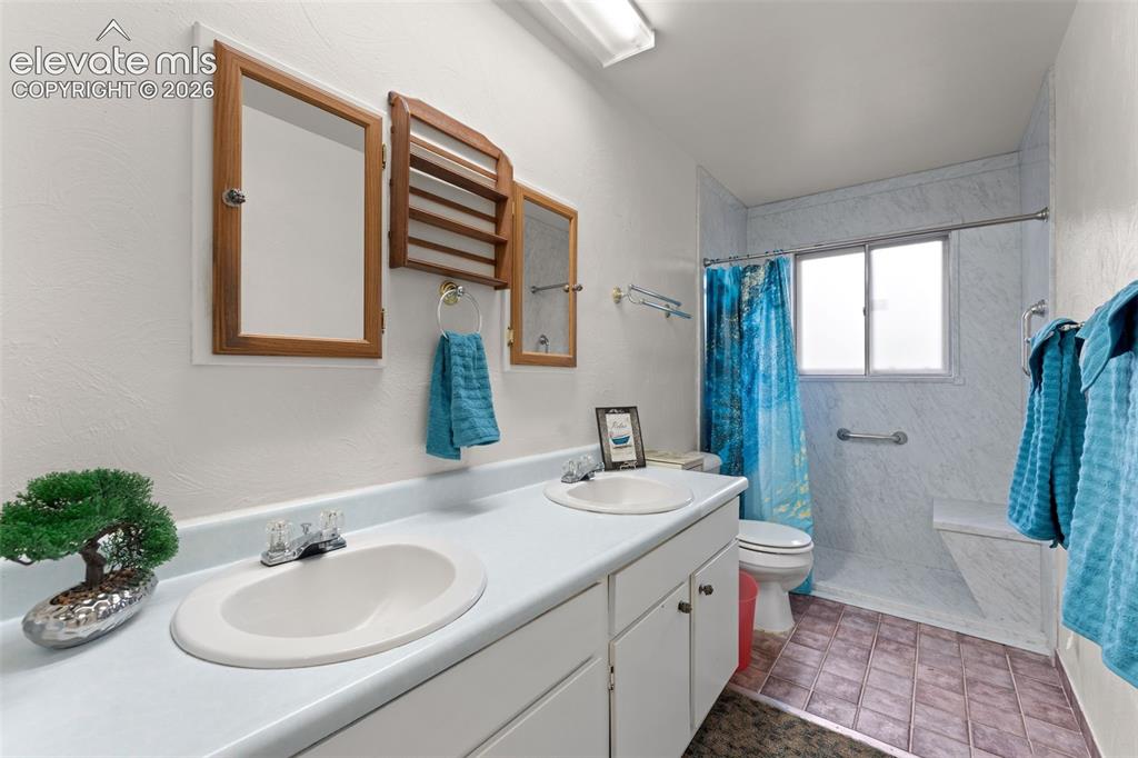 Image 26 of 50: Dual basin vanity with white cabinetry, wood-framed mirrors, and a transluc