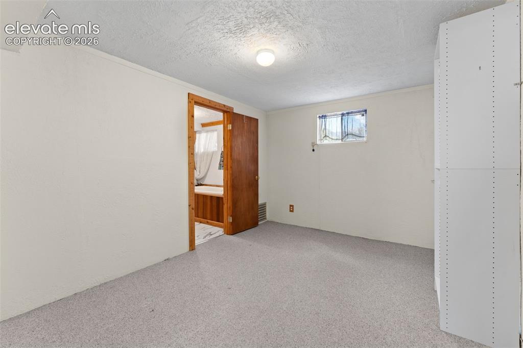 Image 29 of 50: Carpeted flooring, egress window, white painted walls, ceiling-mounted ligh