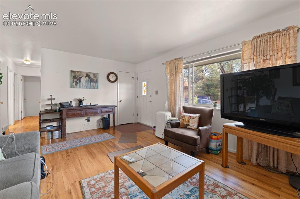 Image 3 of 50: Wood-finish flooring throughout, white walls, and a large window providing