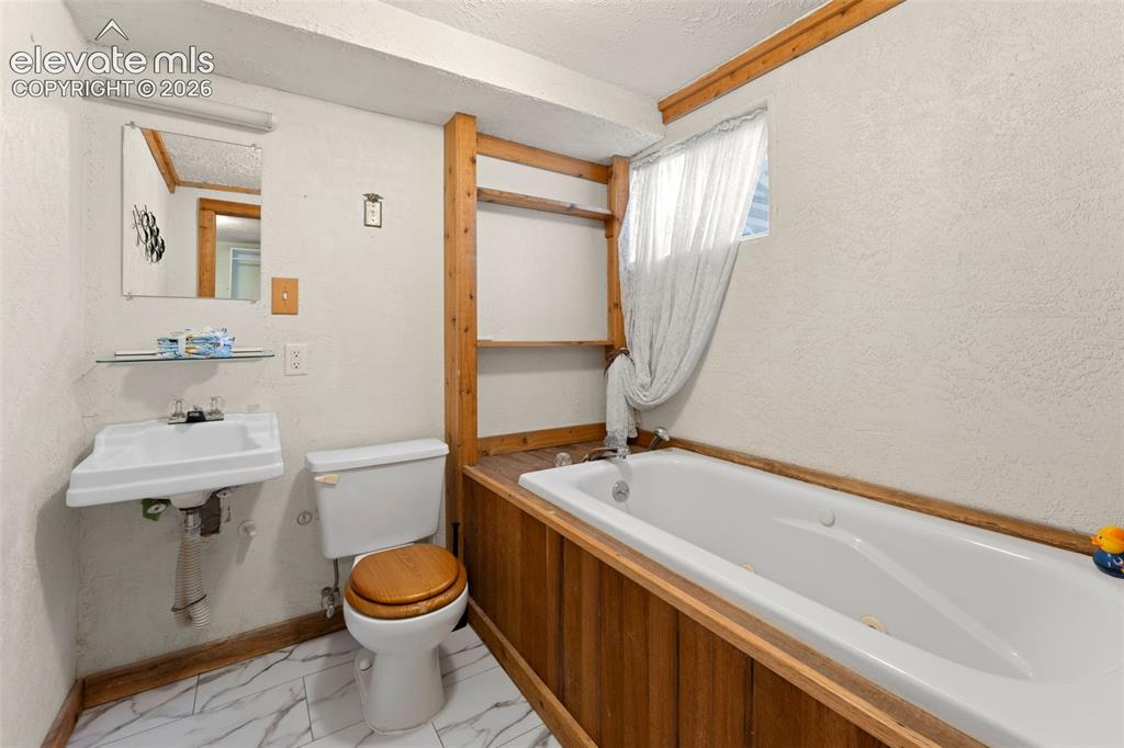 Image 30 of 50: Pedestal sink, wall-mounted mirror, built-in shelving, white bathtub, and w