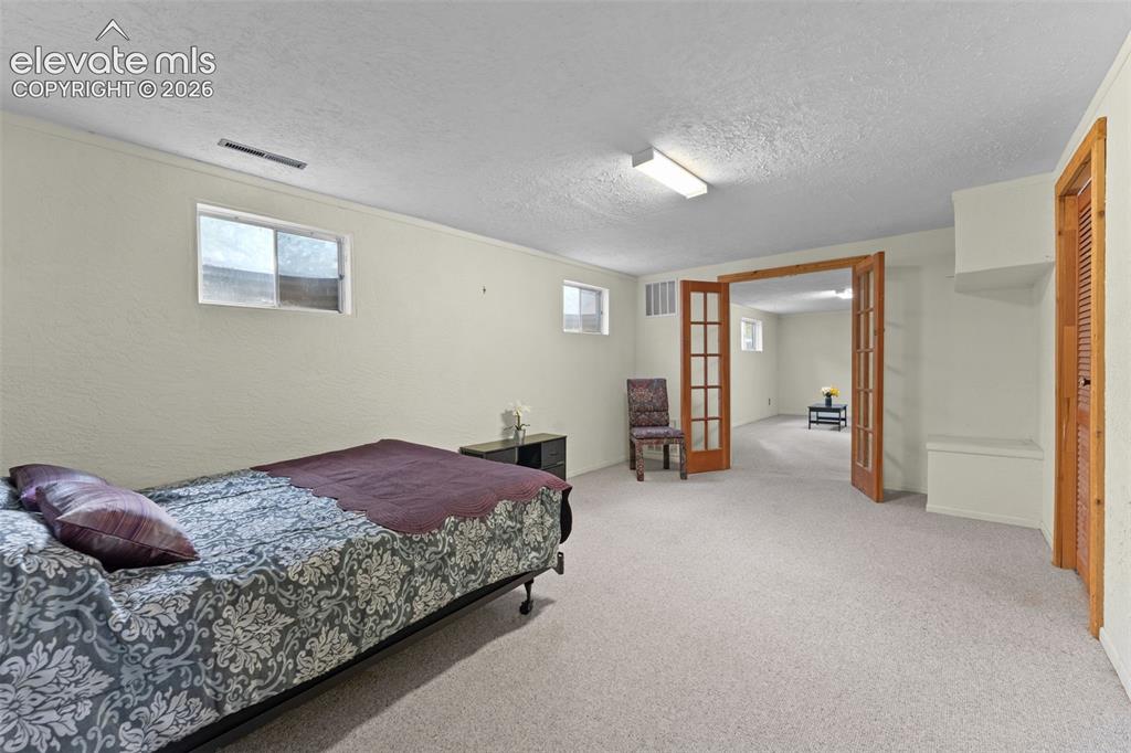 Image 31 of 50: Carpeted flooring, recessed windows, wood-finish French doors, built-in she