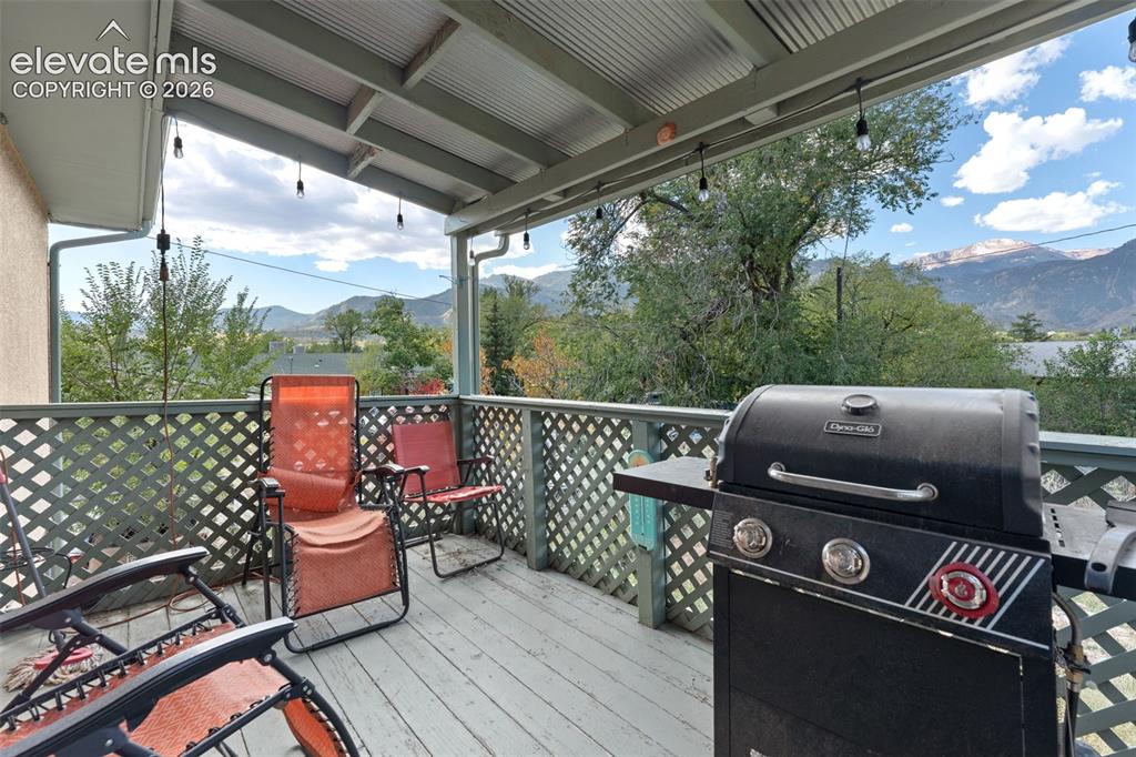 Image 38 of 50: Covered outdoor deck with lattice railing, wood-finish flooring, and mounta