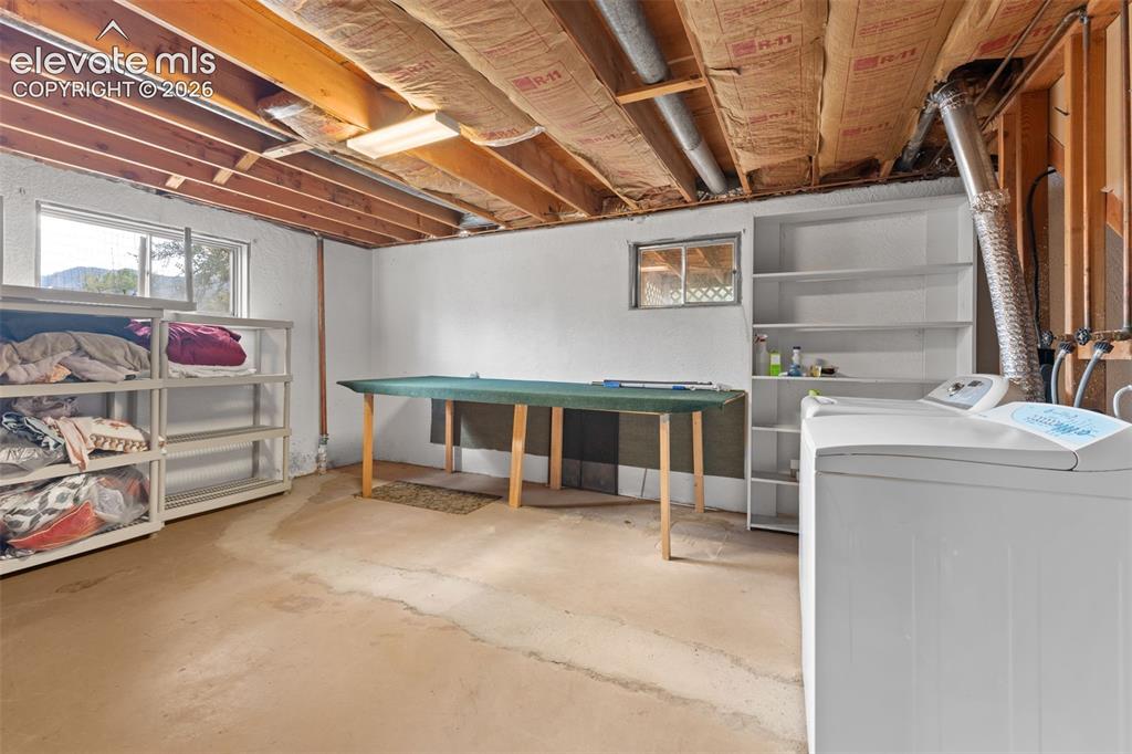 Image 39 of 50: Basement utility area with exposed ceiling joists, concrete flooring, and m