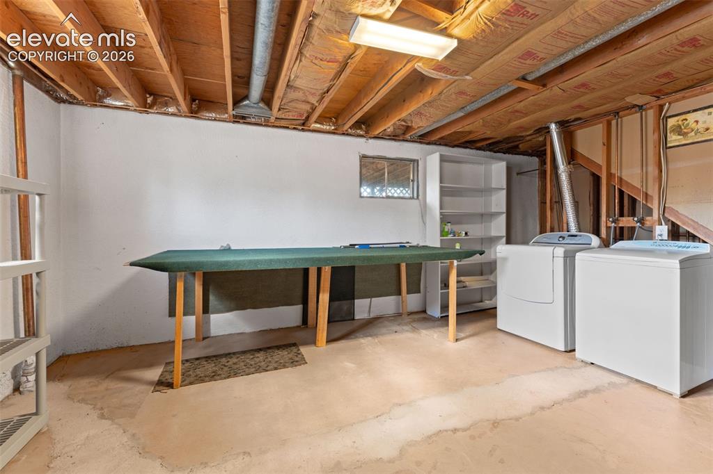 Image 40 of 50: Unfinished basement featuring exposed wood joists, concrete flooring, and w