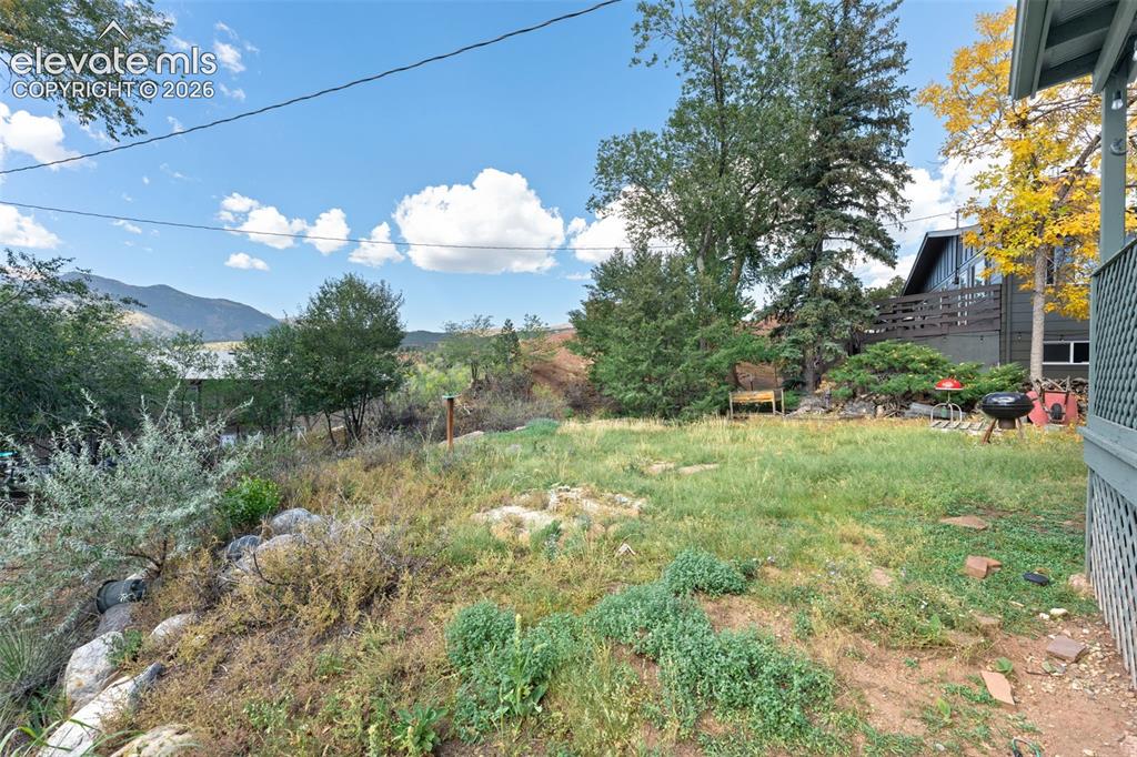 Image 43 of 50: Expansive outdoor space featuring a sloped natural landscape, mature trees,