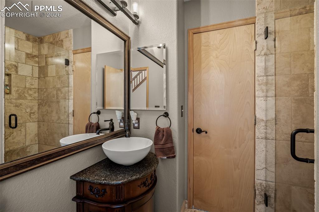 Image 23 of 50: Modern vanity with a vessel sink and dark stone countertop in the main floo