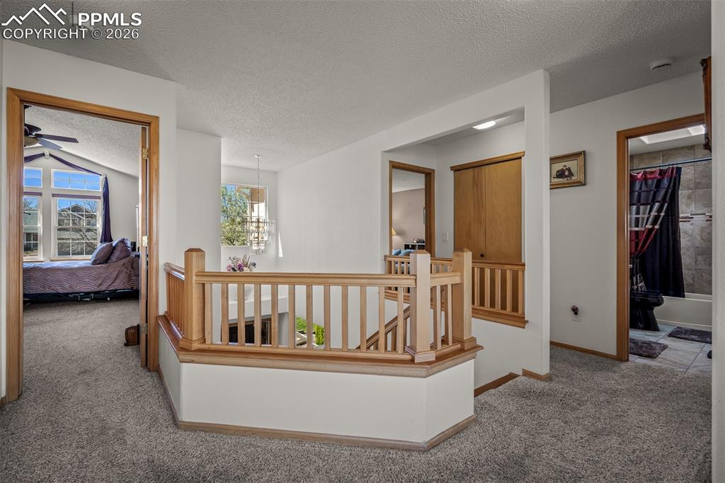 Image 26 of 50: View from loft into primary bedroom.  