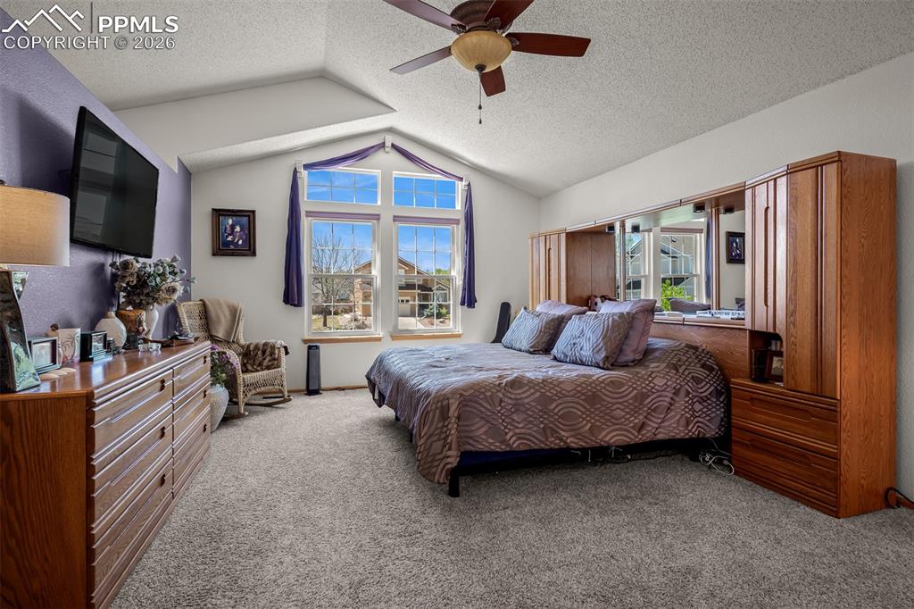 Image 30 of 50: Vaulted ceilings enhance the large primary bedroom featuring a ceiling fan 